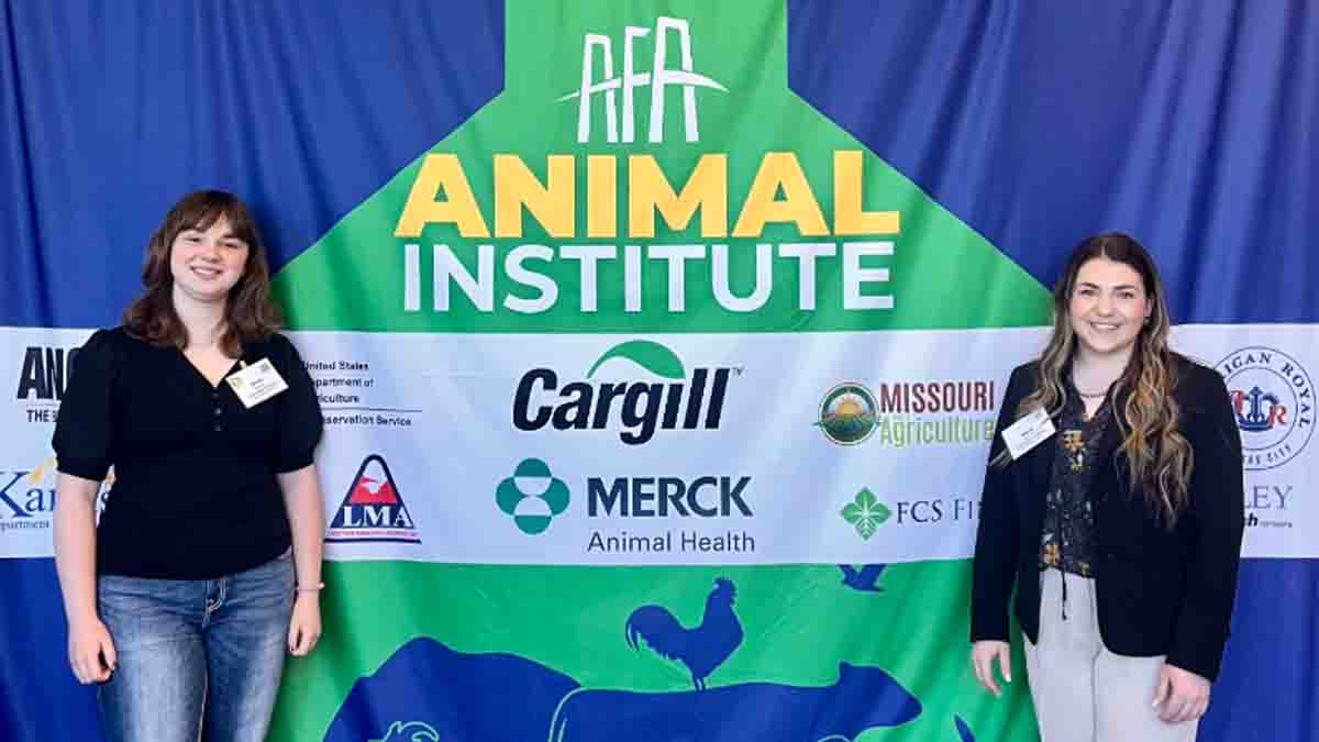 Two women standing in front of an animal institute banner.
