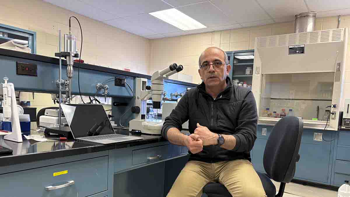 A man sitting next to a laptop and lab equipment.
