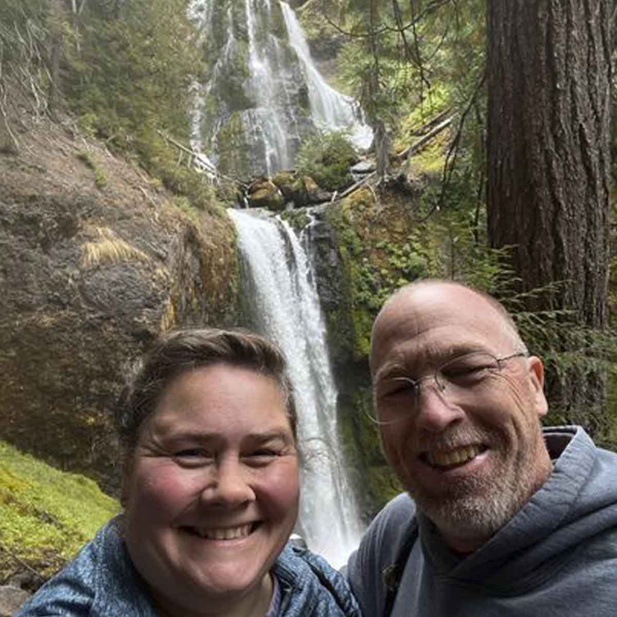 A photo of a woman and man with a waterfall in the background.