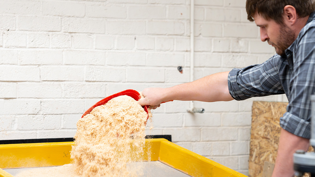 Student works with sawdust used in printing process.