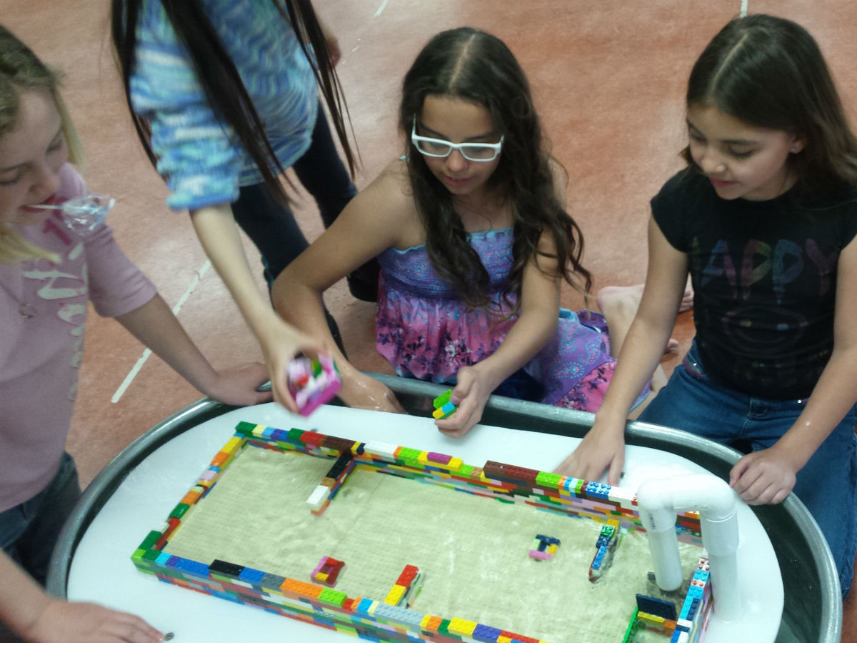 Children playing with legos in water.